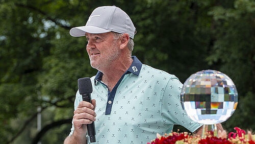 Mark Brown, Sieger 2025, hält ein Mikrofon und spricht. Neben ihm steht der Glaspokal. Er trägt ein weisses Cap und ein hellblaues Shirt.