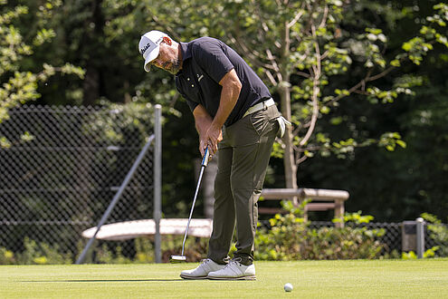 Van Phillips beim Putt. Er ist dunkel gekleidet mit weissem Cap.